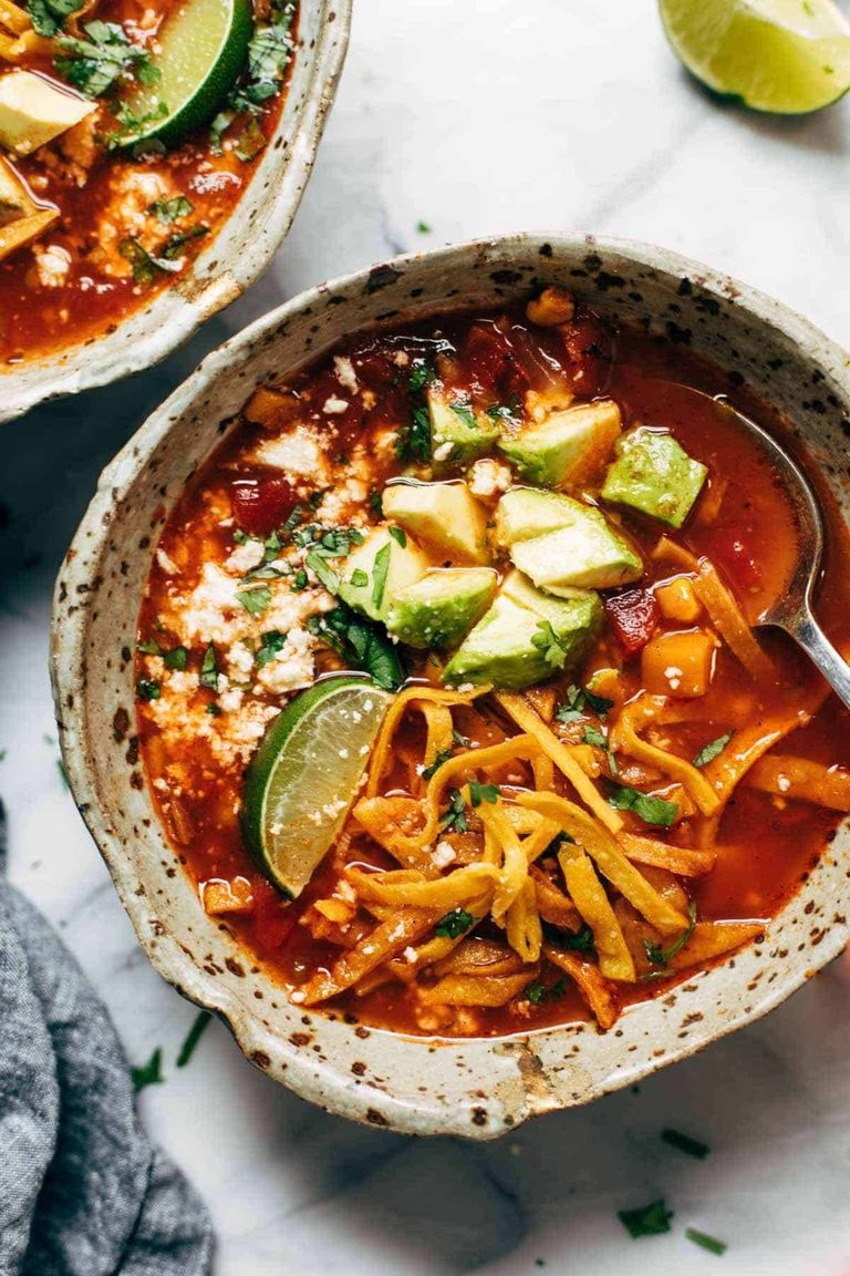 Sweet potato tortilla soup in a bowl with avocado and tortillas on top.
